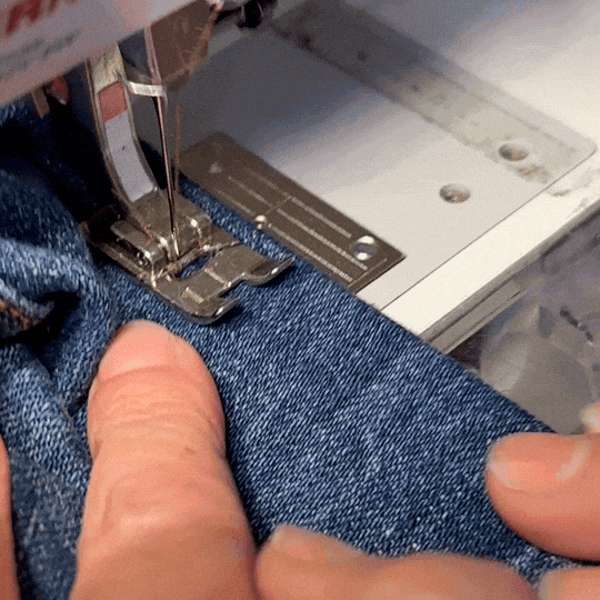 hands guiding jeans on a sewing machine 